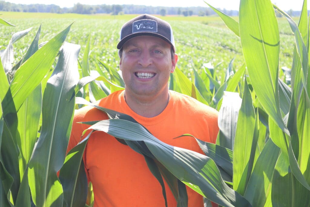 Smiling man in orange shirt in cornfield